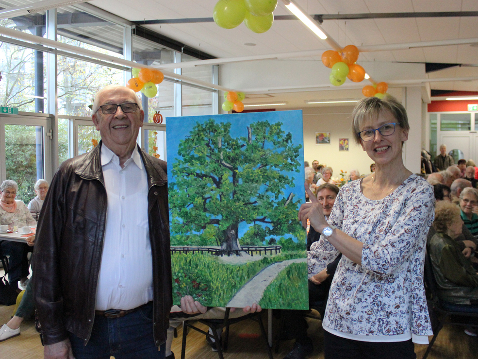 Stammgast Karl Gürth bedankte sich bei Eichenhof-Leiterin Claudia Kirtzel mit seinem Gemälde von der „Kalten Eiche“ für fünf gelungene Jahre im Begegnungszentrum.