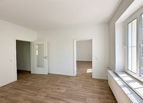 Lichtdurchflutete Wohnung mit weißen Raufaserwänden, Holzoptikfußboden und schönen großen Fenstern mit Fensterkreuz in einem frisch sanierten Altbau im Wohnquartier Biethe in Dessau-Roßlau.