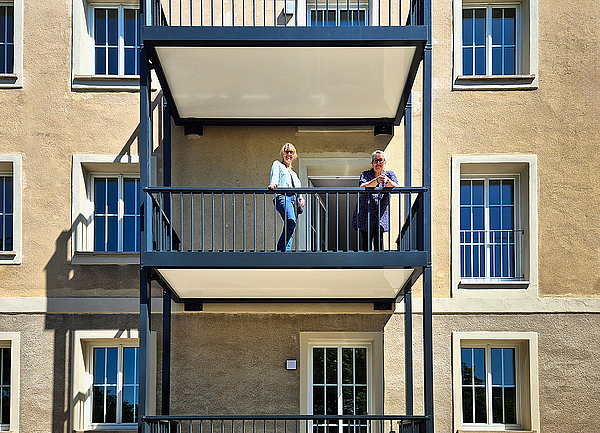 TAG-Marketing-Ansprechpartnerin Susan Nölte steht mit Mieterin Frau Kraul auf dem neu angebauten Balkon im frisch sanierten 1950er-Jahre-Altbau in Dessau-Roßlau.