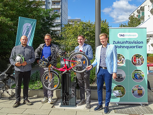 Vier Vertreter der Stadt Erfurt und der TAG Wohnen präsentieren ein montiertes Fahrrad an der neu eröffneten Fahrrad-Reparaturstation am Berliner Platz in Erfurt.