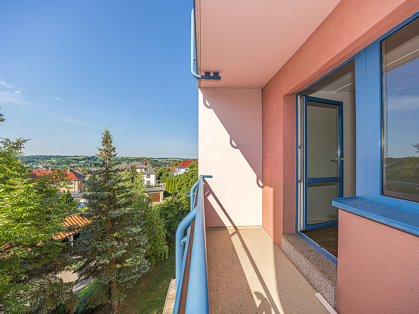 Balkon einer Wohnung Am Holländer in Döbeln mit Blick ins Grüne auf Bäume und Nachbarhäuser an einem sonnigen Tag