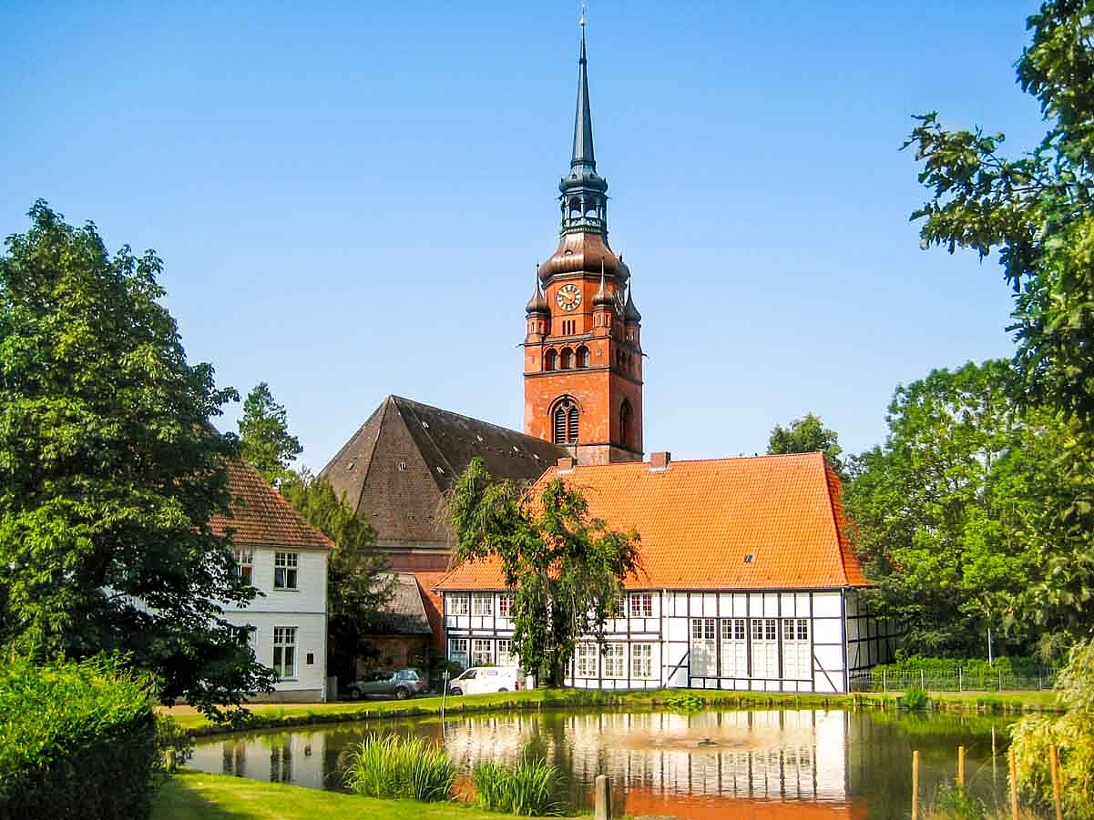 Kleiner Teich umgeben von Grün und im Hintergrund die alte Zierzienserinnenabtei in Itzehoe