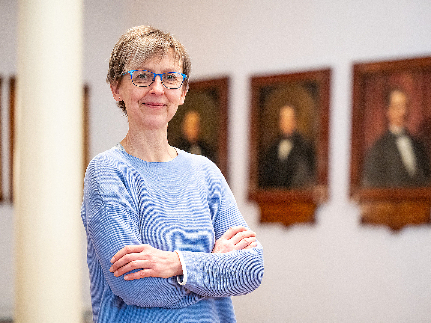 Porträtaufnahme von Claudia Kirtzel vor einer Bildergalerie 