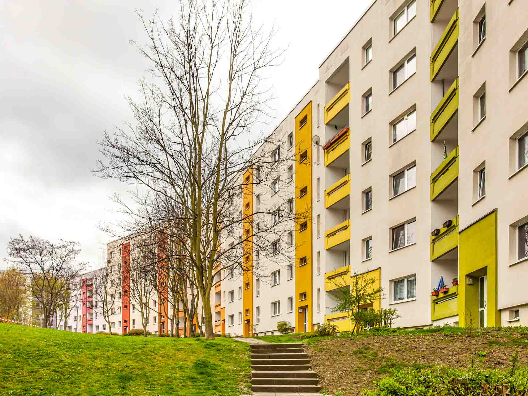 Grüner Innenhof mit farbenfrohen Hauseingängen.