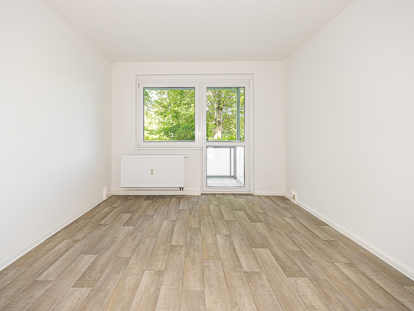 Leeres, helles Wohnzimmer mit Holzoptik-Boden, großem Fenster und Balkontür in der Lommatzscher Straße in Döbeln