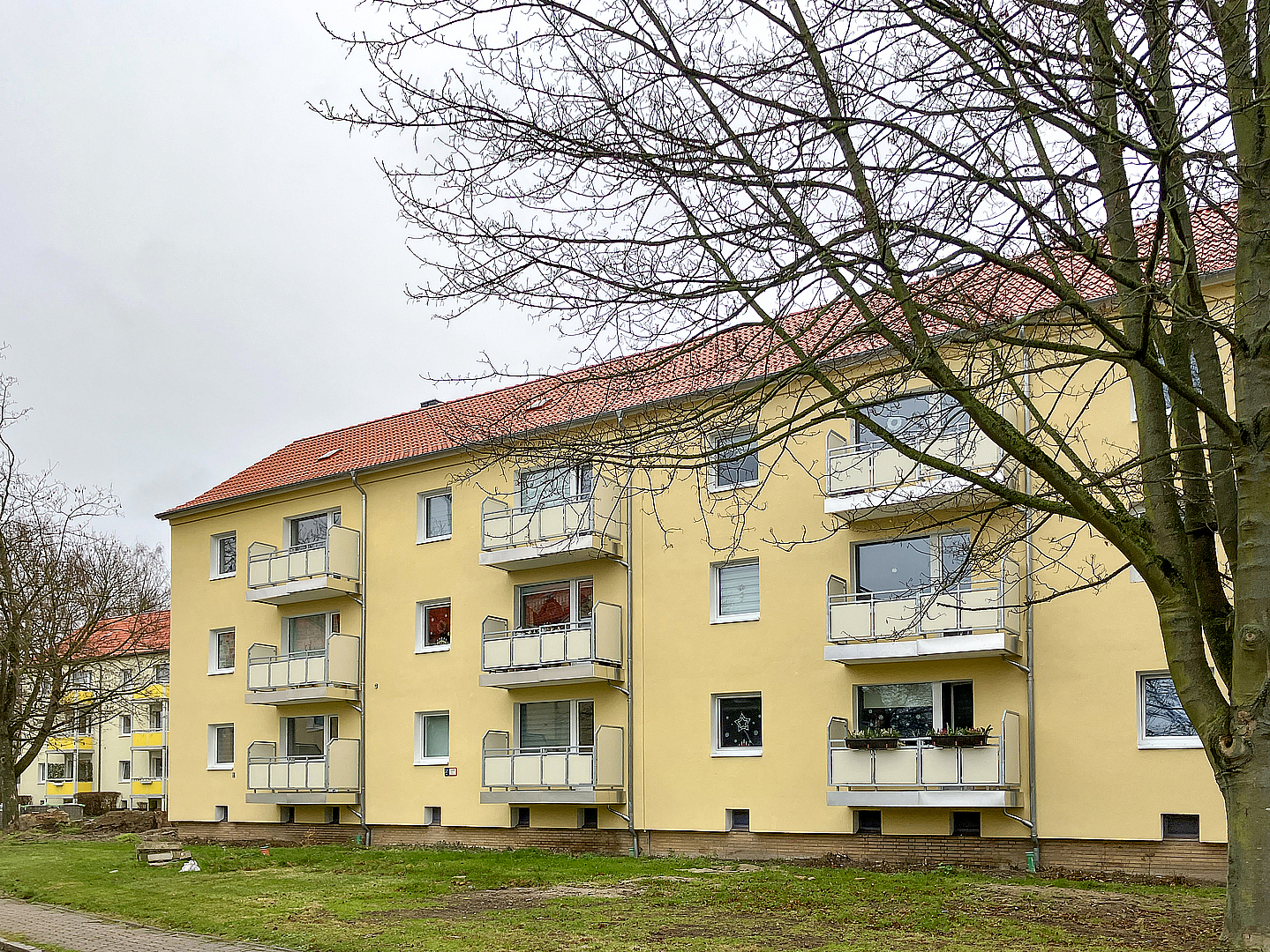 Modernisierter Wohnkomplex mit 48 Wohnungen und gelber Fassade am Ilschenberg in Salzgitter, energetisch grundsaniert von TAG Wohnen.