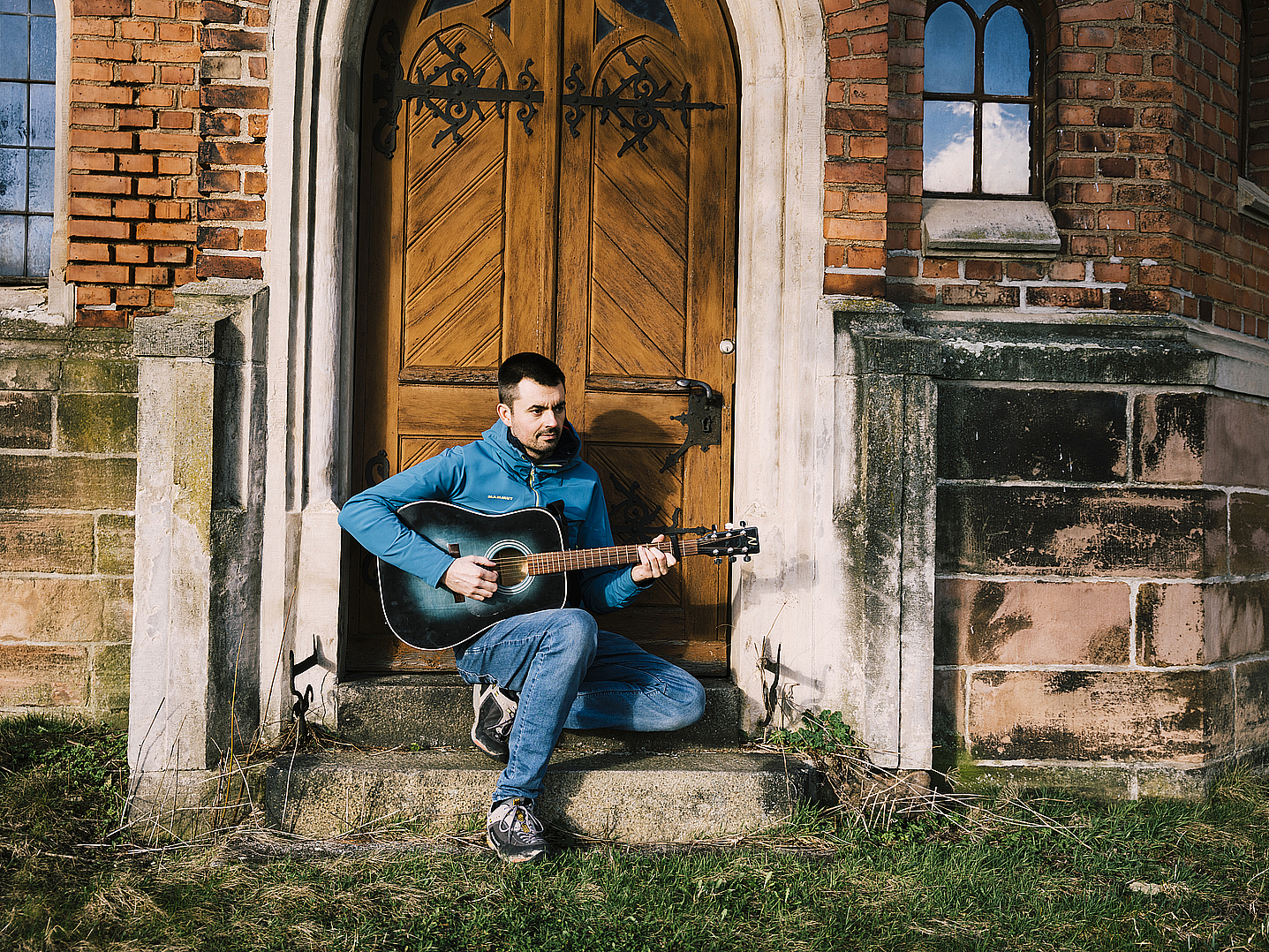 Christian Mende mit Gitarre vor der Kirche Mohlsdorf, in einem Nachbarort von Greiz.