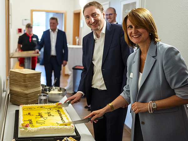 Die Geschäftsführerin des Pflegedienstes Kraft Melanie Vogel und die Gesamtleitung Immobilienmanagement der TAG Wohnen Claudius Oleszak schneiden bei der Jubiläumsfeier in Hermsdorf gemeinsam den Jubiläumskuchen zur 10-jährigen Kooperation an.