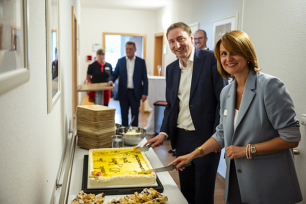 Die Geschäftsführerin des Pflegedienstes Kraft Melanie Vogel und die Gesamtleitung Immobilienmanagement der TAG Wohnen Claudius Oleszak schneiden bei der Jubiläumsfeier in Hermsdorf gemeinsam den Jubiläumskuchen zur 10-jährigen Kooperation an.