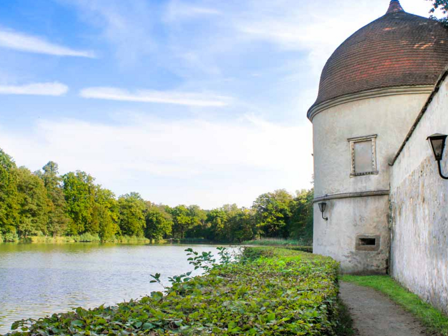 Ein Spaziergang lohnt sich im Schlosspark Hermsdorf entlang der Schlossmauer mit Türmchen und See.