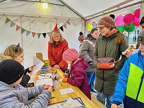Kinder und Erwachsene basteln Weihnachtsschmuck. 