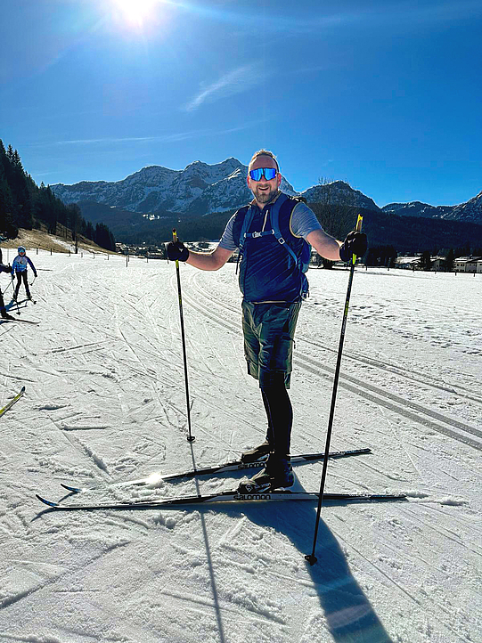 Christian Zimmermann läuft Langlaufski vor einer schönen Bergkulisse. 