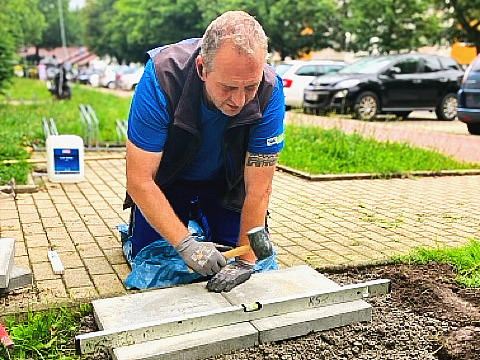 Sirko Pfützner ist Teamleiter im Hermsdorfer Facility Management der TAG Wohnen und verlegt hier Gehwegplatten.