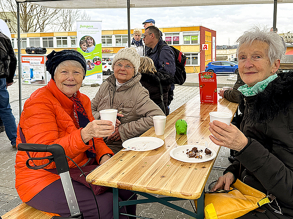Drei ältere Damen trinken Kaffee und essen Kuchen.  