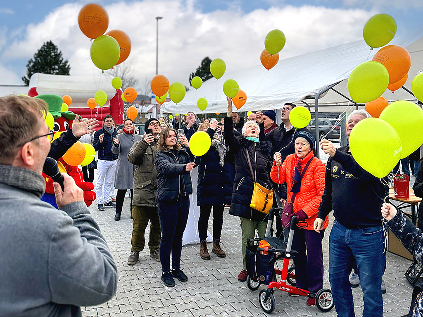 Die Gäste lassen grüne und orangene Luftballons in den Himmel steigen.