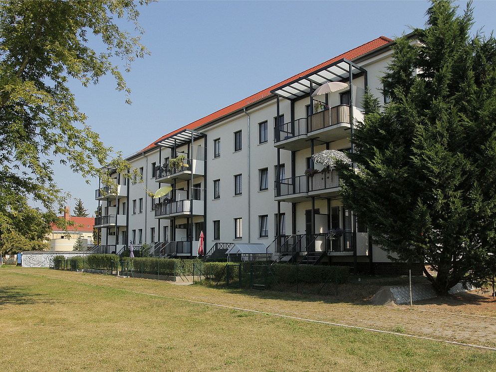 Cremefarbenes Mehrfamilienhaus mit Balkonen im grünen Brandenburg an der Havel