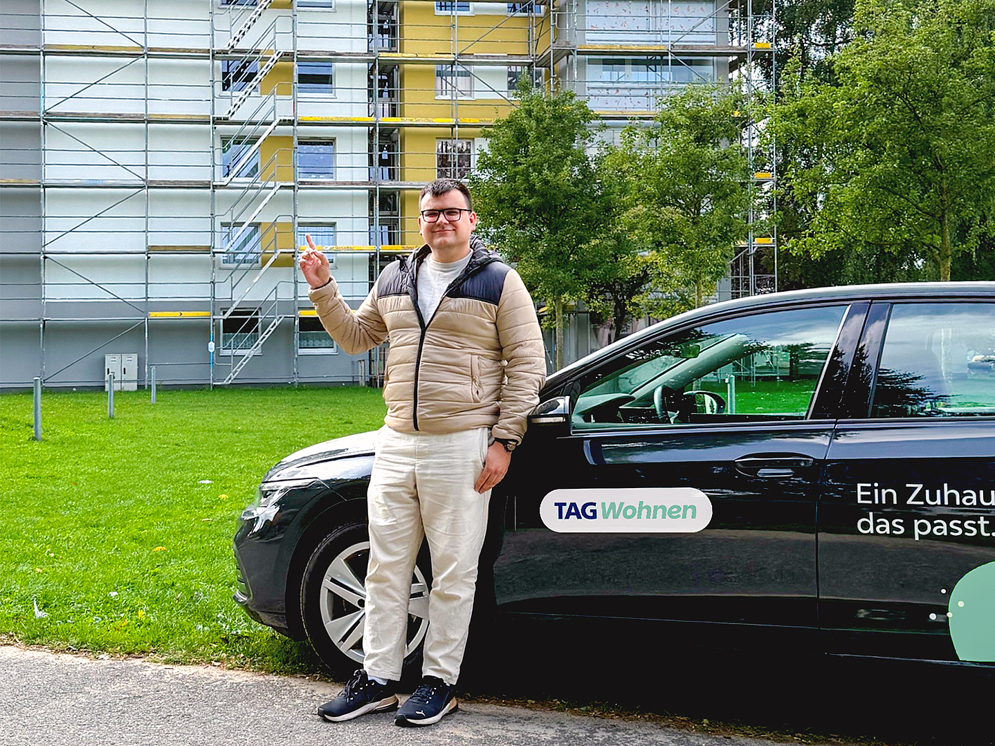 Rick Gensch vor einem Firmenfahrzeug der TAG Wohnen und einem in Sanierung befindlichen Wohngebäude in Elmshorn