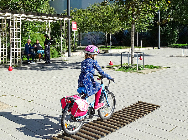 Kind mit Helm fährt mit dem Fahrrad über einen Übungsparcours der Thüringer Polizei vor dem Stadtteiltreff Berolina in Erfurt-Nord.