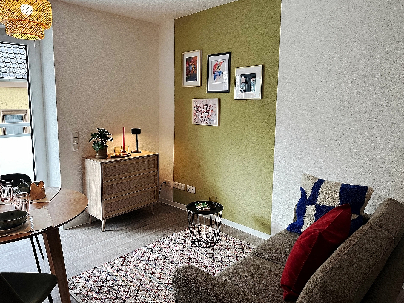 Eingerichtetes gemütliches Wohnzimmer mit einer Couch und einem Esstisch sowie einem Balkon