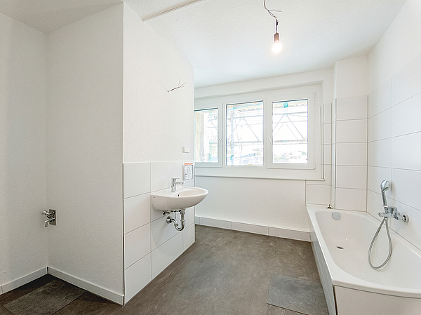 Frisch modernisiertes Badezimmer mit Badewanne, Waschbecken und großem Fenster in einer sanierten Wohnung des Zehngeschossers in der Otto-Nagel-Straße im Kannenstieg.