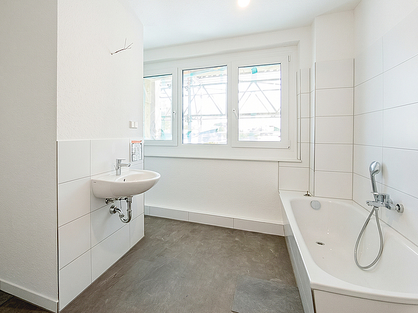 Frisch modernisiertes Badezimmer mit Badewanne, Waschbecken und großem Fenster in einer sanierten Wohnung des Zehngeschossers in der Otto-Nagel-Straße im Kannenstieg.