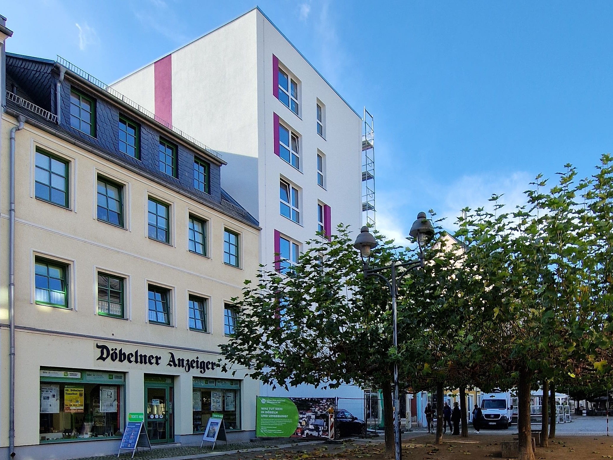 Auf der linken Seiter stehen Häuser in rosa, gelb und weiß und auf der rechten Seite sind ein paar bäume bepflanzt