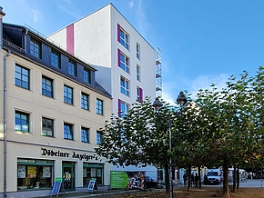 Auf der linken Seiter stehen Häuser in rosa, gelb und weiß und auf der rechten Seite sind ein paar bäume bepflanzt