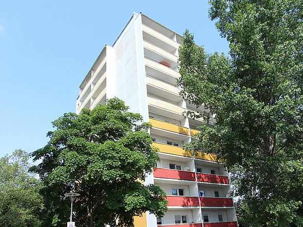 Farbenfrohes Mehrfamilienhaus mit Balkonen, eingebettet in eine grüne Umgebung mit großen Bäumen im Stadtteil Gera-Lusan