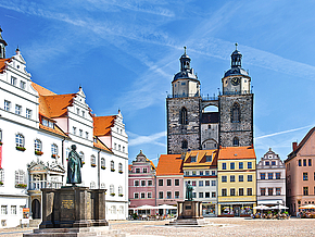 Blick auf den charmanten Wittenberger Marktplatz mit seinen farbenfrohen Häusern, dem historischen alten Rathaus und der beeindruckenden Martin-Luther-Statue