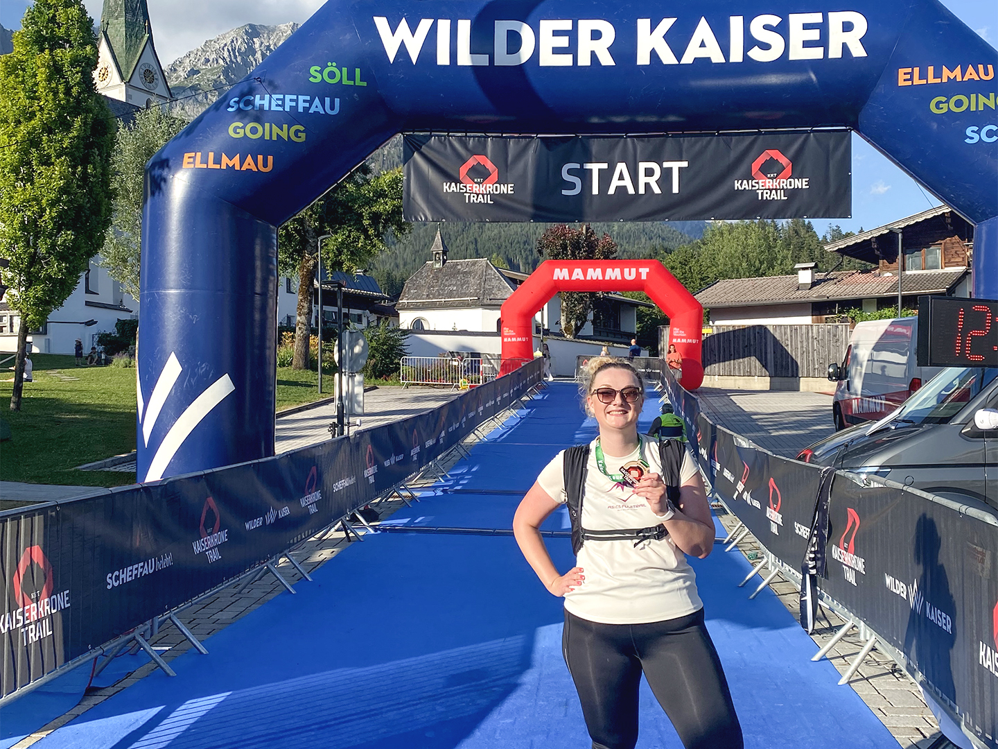 Das Bild Zeigt Dagmar Schmidt im Zieleinlauf eines Laufwettbewerbs, lächelnd und mit Medaille um den Hals