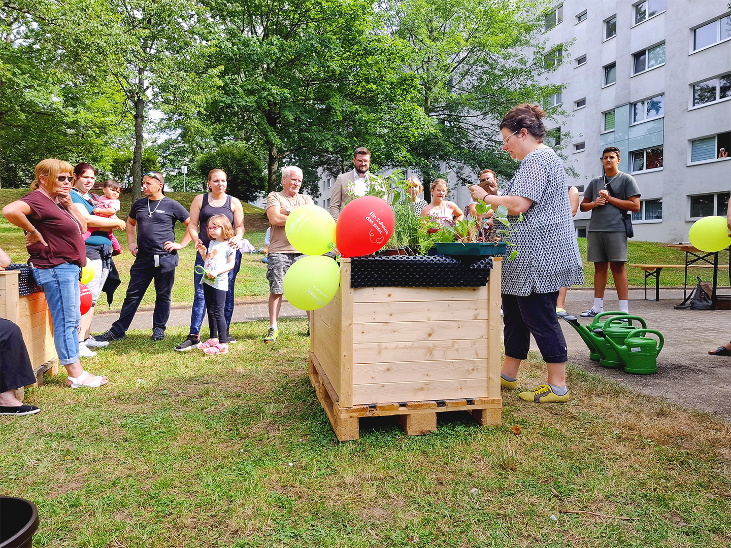 Start der Ackerpause: Erste Bepflanzungen der Hochbeete in Chemnitz-Kappel Eine Frau steht am Hochbeet und erklärt einer Gruppe von Menschen wie man dieses bepflanzt.