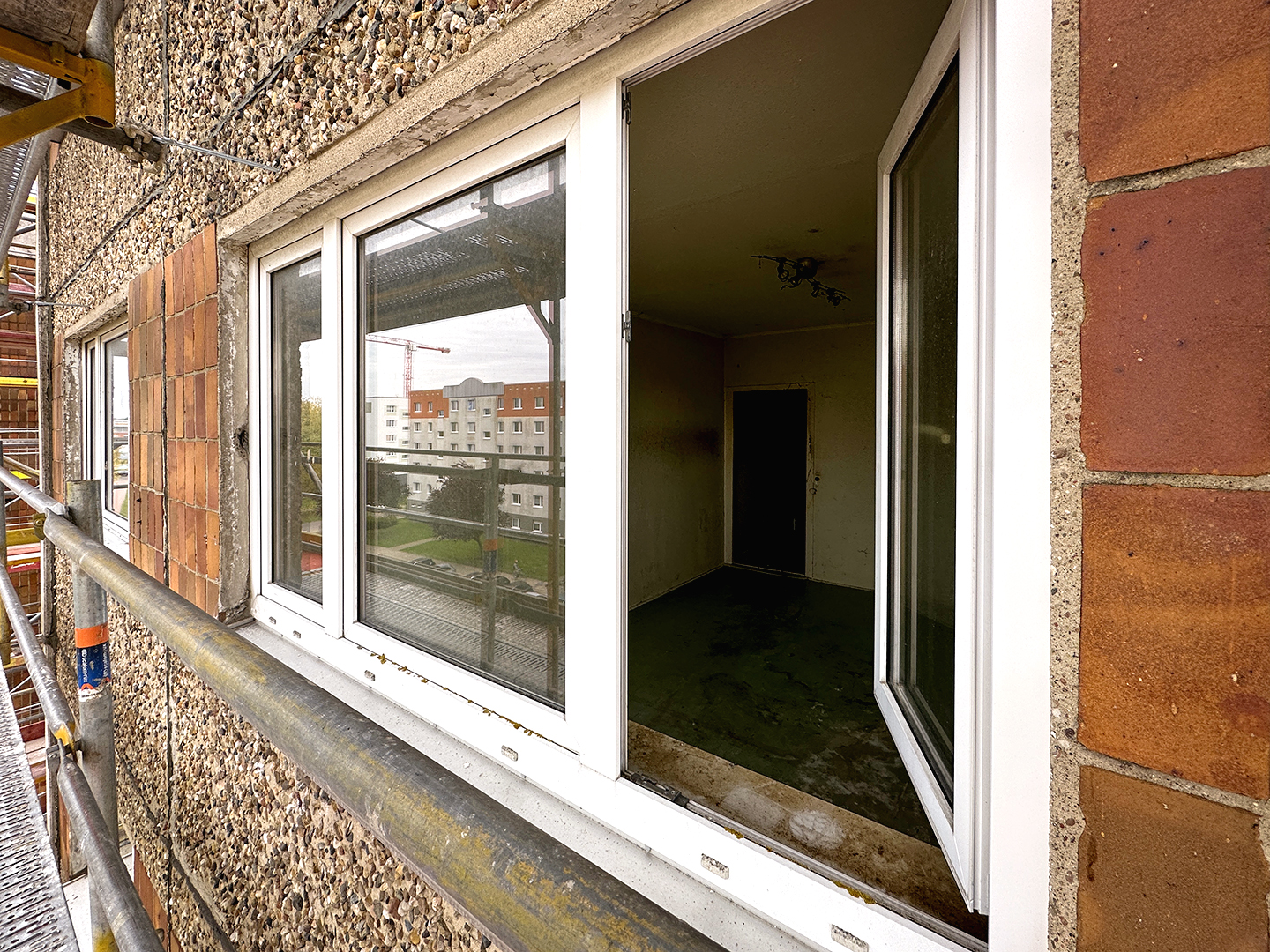 Die alte Fassade eines Mehrfamilienhauses in Plattenbauweise vor Sanierungsstart.
