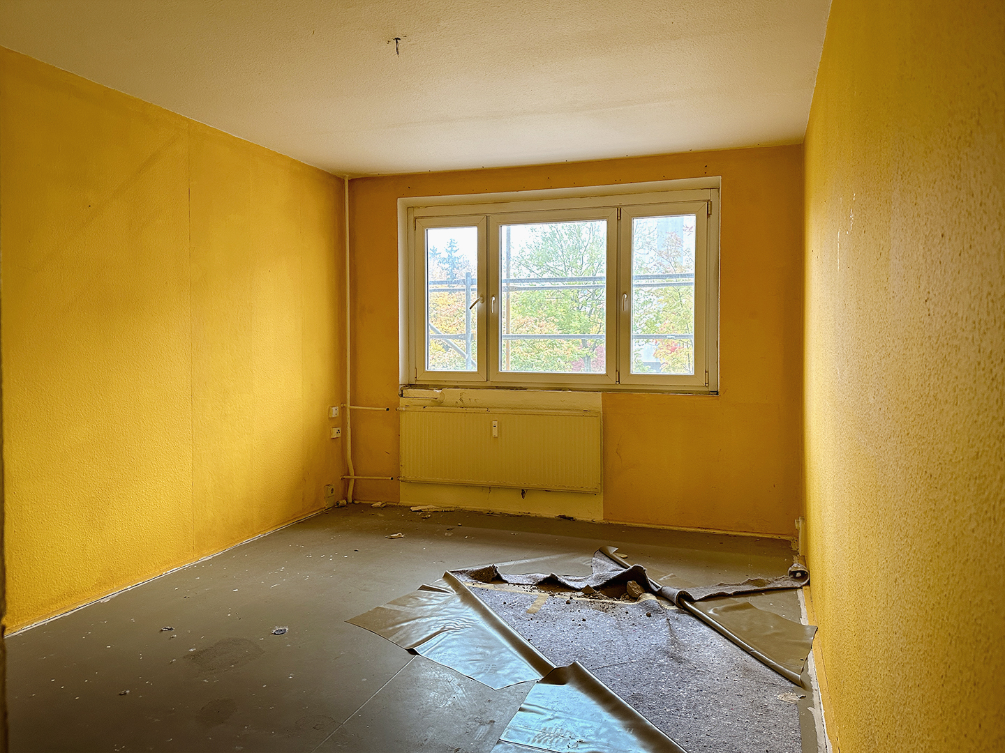 Gelb gestrichenes Zimmer in einer Plattenbauwohnung in einem Sanierungsprojekt in Greifswald.
