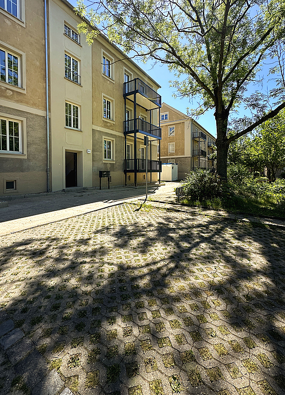 Frisch sanierter Altbau aus den 1950er Jahren mit gereinigter sandfarbener Fassade und neu angebauten großen Balkonen mit dunkler, dezenter Balkonbrüstung im Wohnquartier Biethe in Dessau-Roßlau