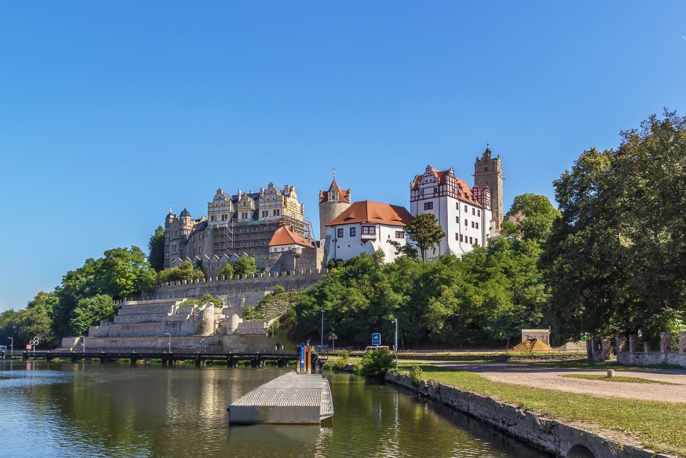 Das große Schloss Bernburg ist im Hintergrund zu sehen und davor fließt der Fluss Saale entlang