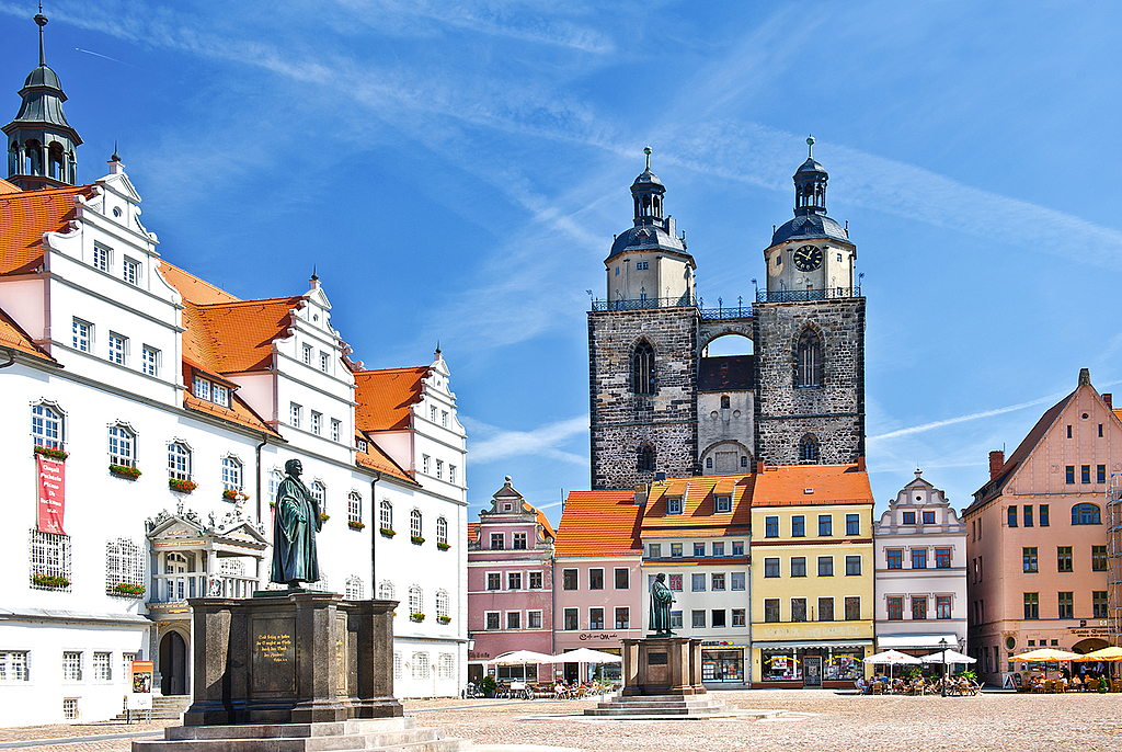 Blick auf den charmanten Wittenberger Marktplatz mit seinen farbenfrohen Häusern, dem historischen alten Rathaus und der beeindruckenden Martin-Luther-Statue